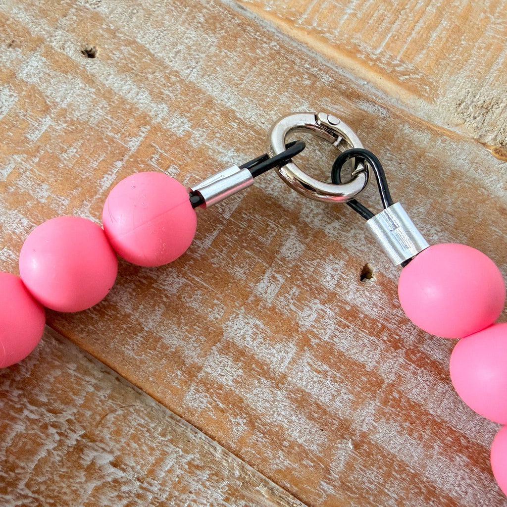 Pink beaded keychain with metal clasp on a wooden surface