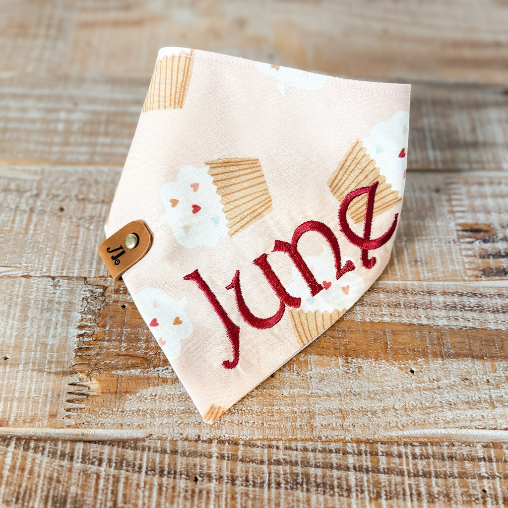 Fabric bandana with 'June' printed on it, featuring a sun design, on a wooden surface.