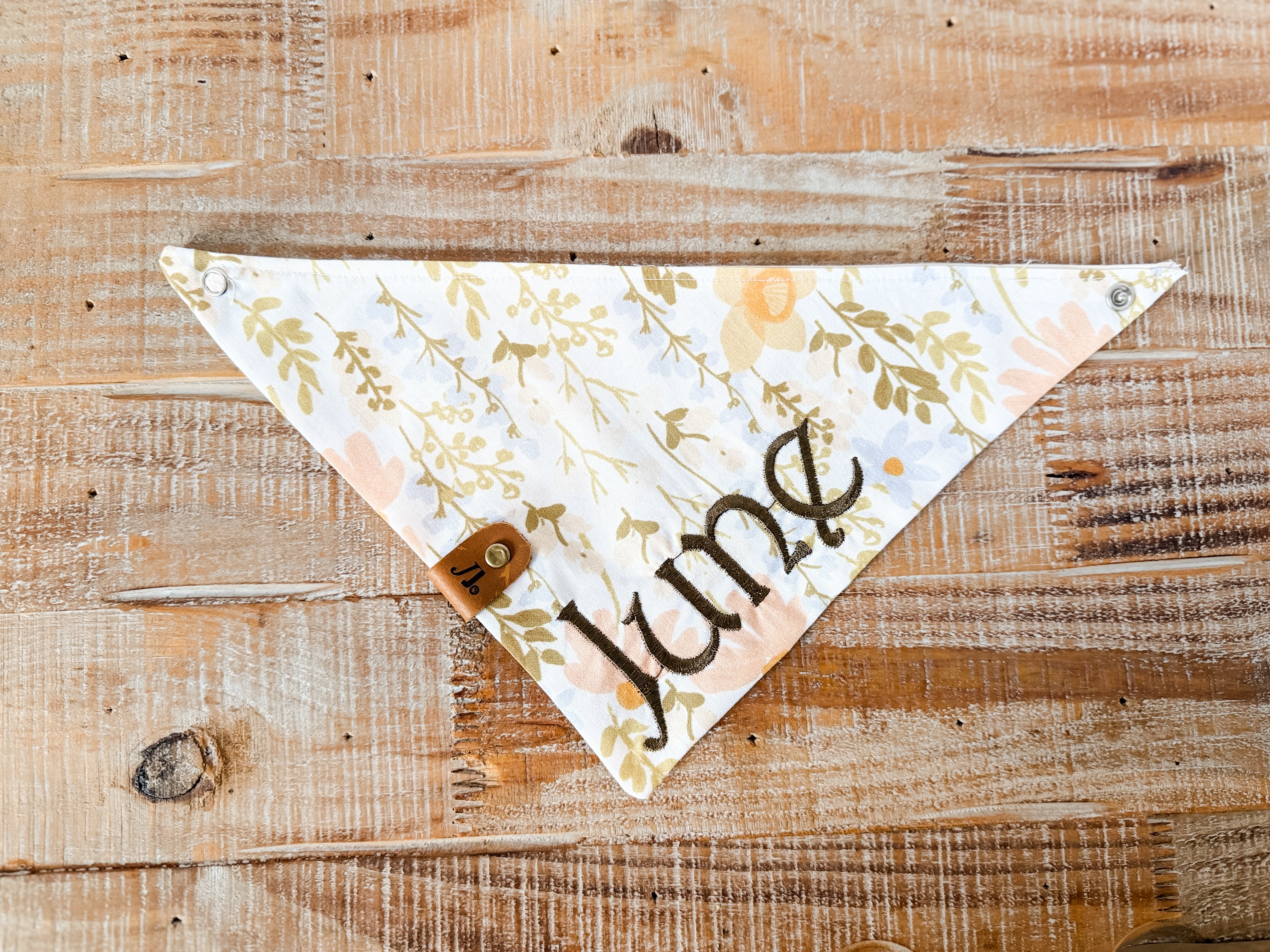 Floral patterned bandana with 'June' text on a wooden surface