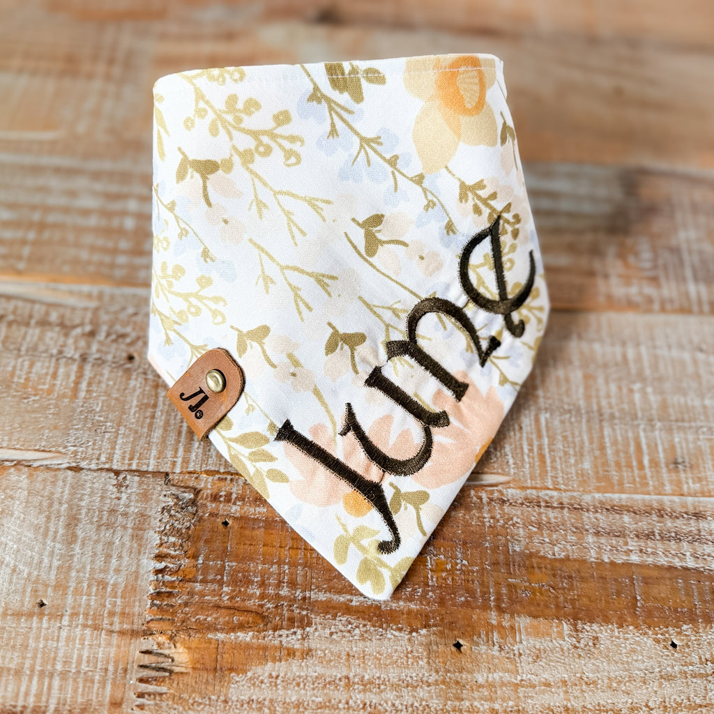 Floral-patterned bandana with 'June' printed on it, placed on a wooden surface.