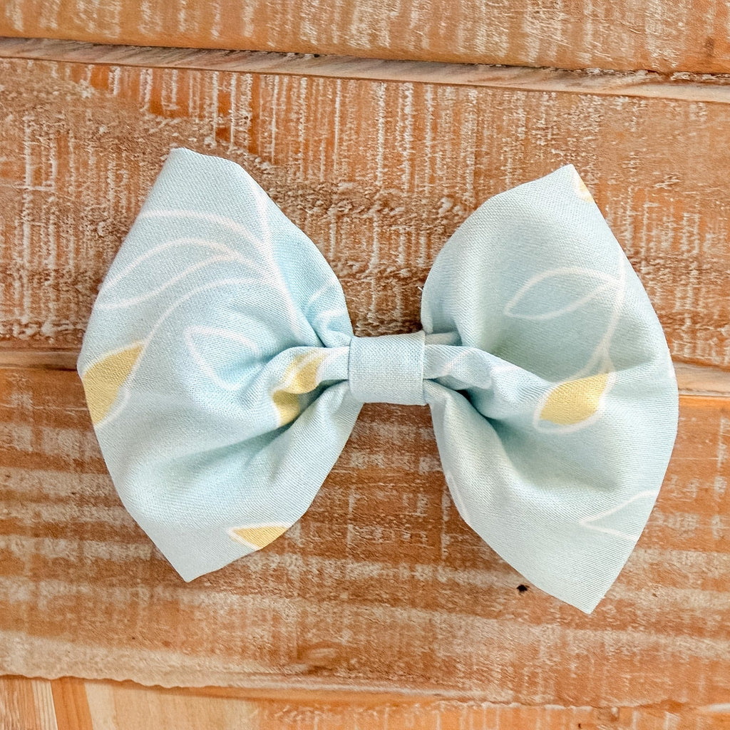 Light blue bow with gold accents on a wooden surface