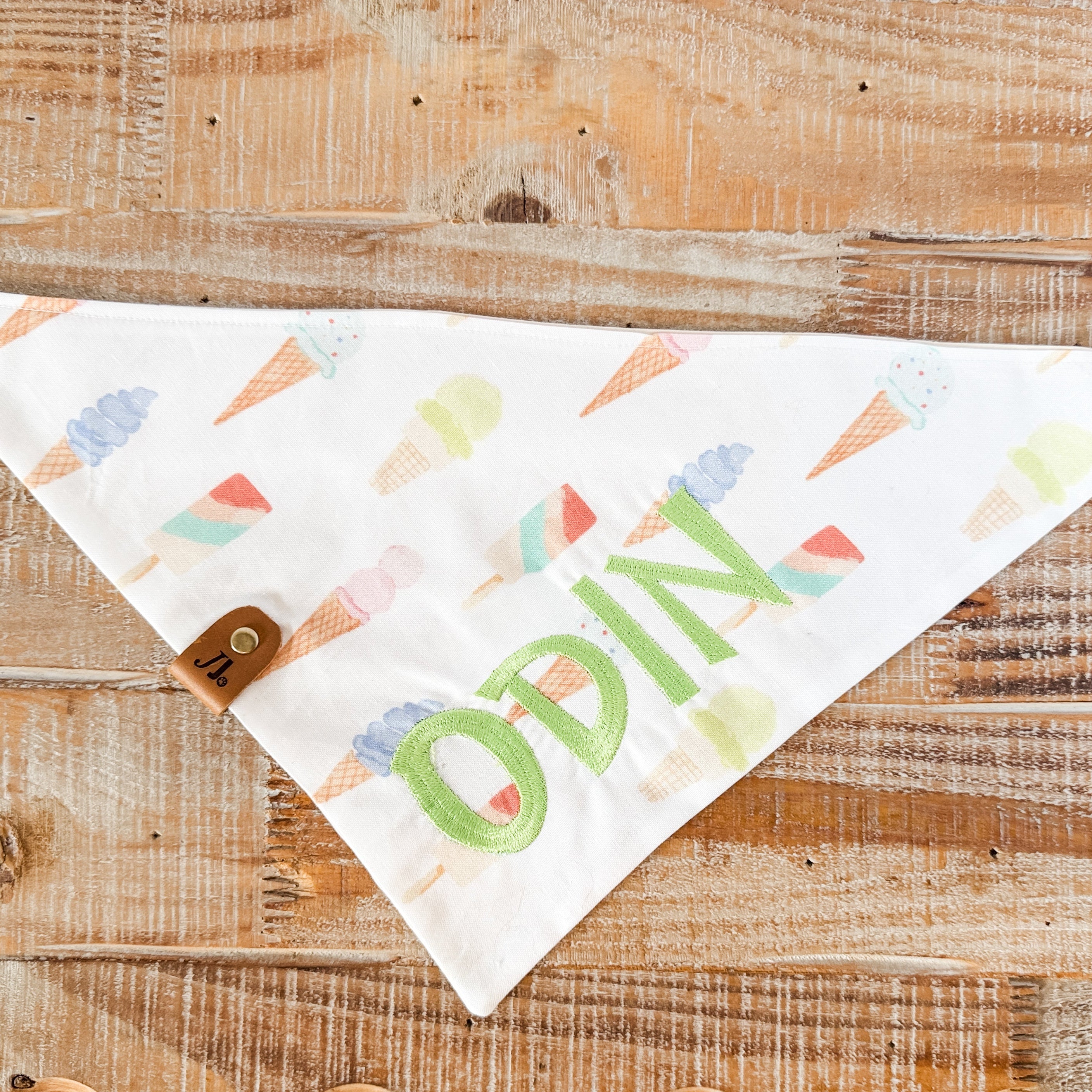 Fabric bandana with colorful ice cream cone pattern and 'ODIN' text on a wooden surface
