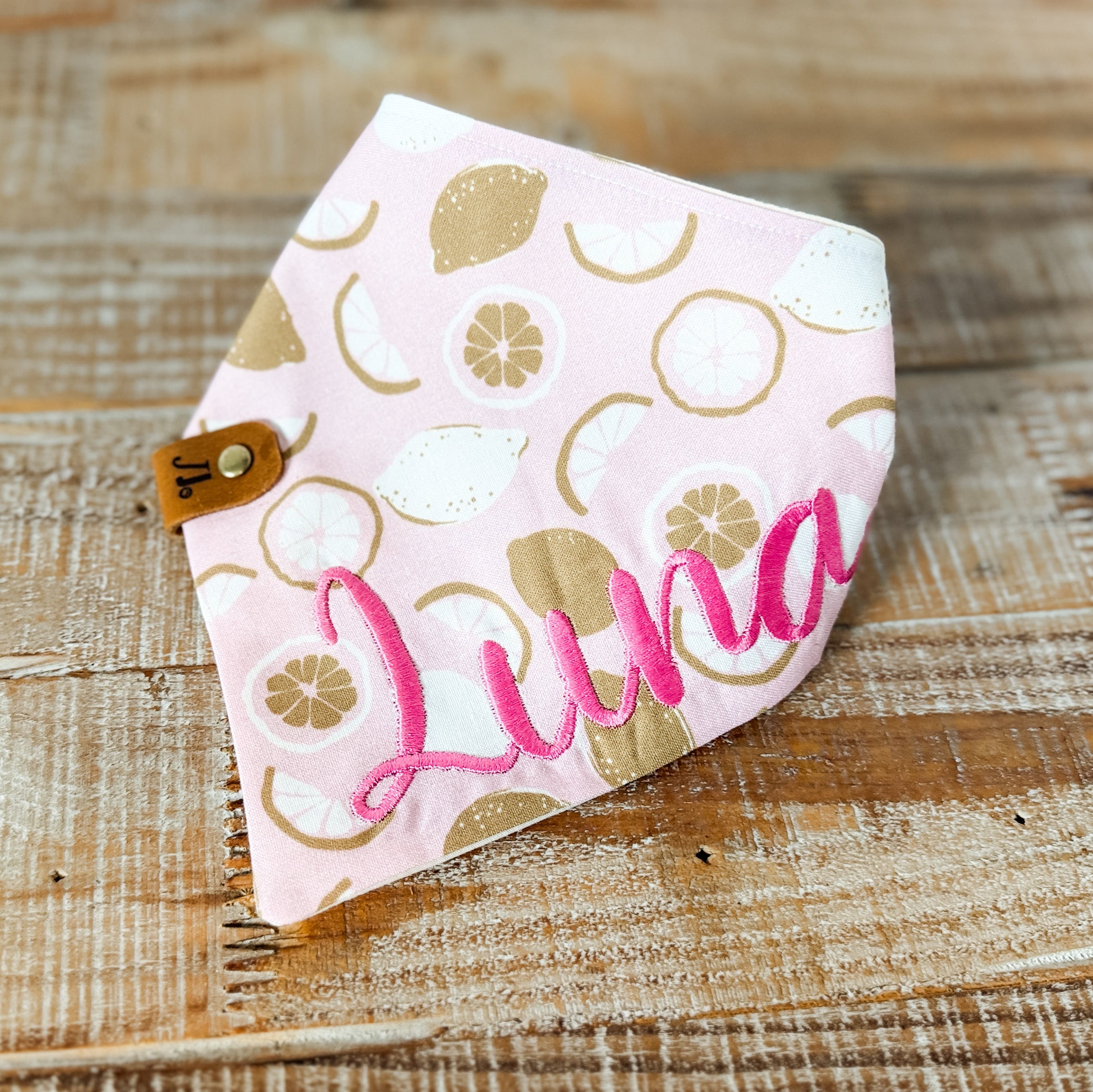Fabric bandana with floral pattern and 'Luna' embroidery on a wooden surface