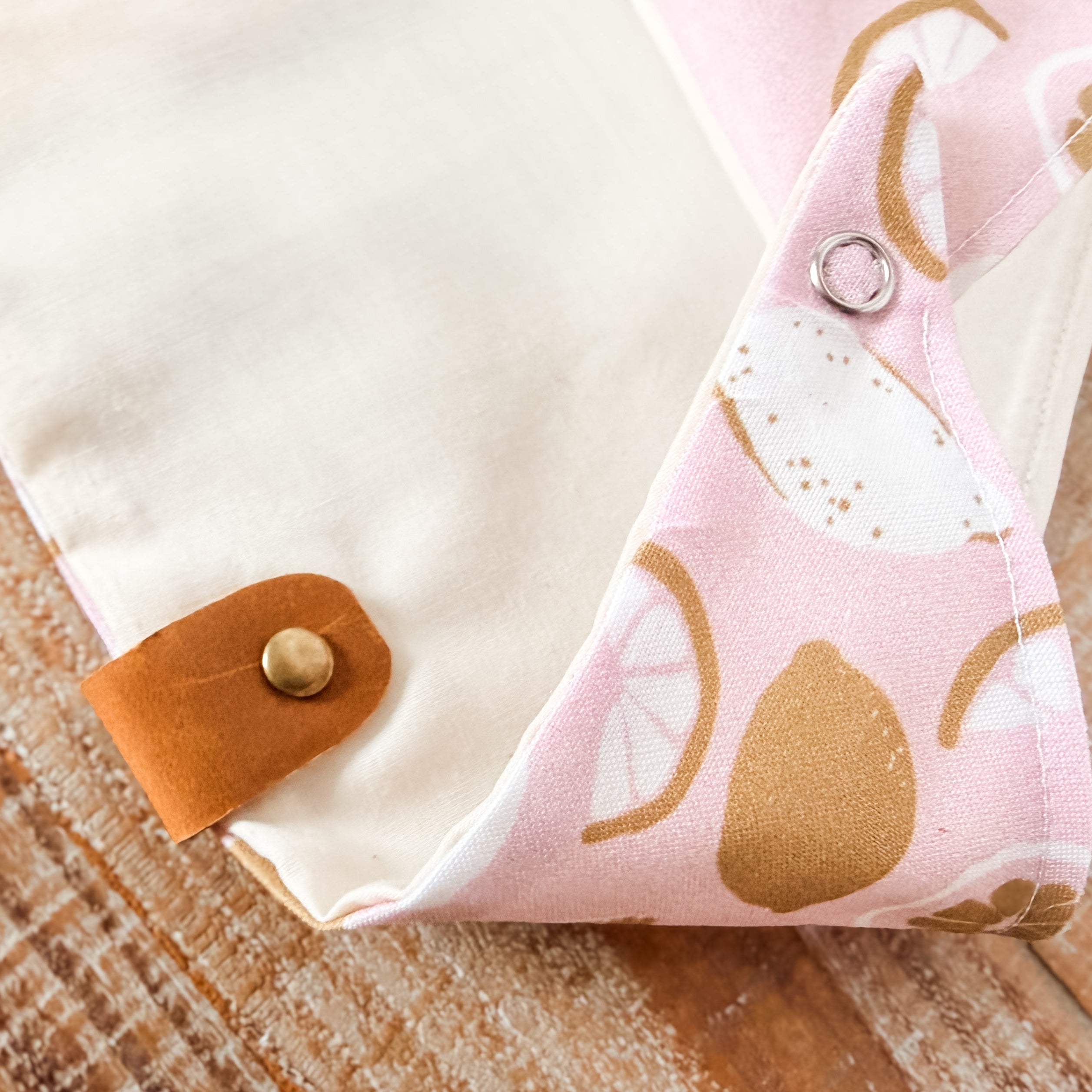 Fabric with pink and gold pattern on a wooden surface