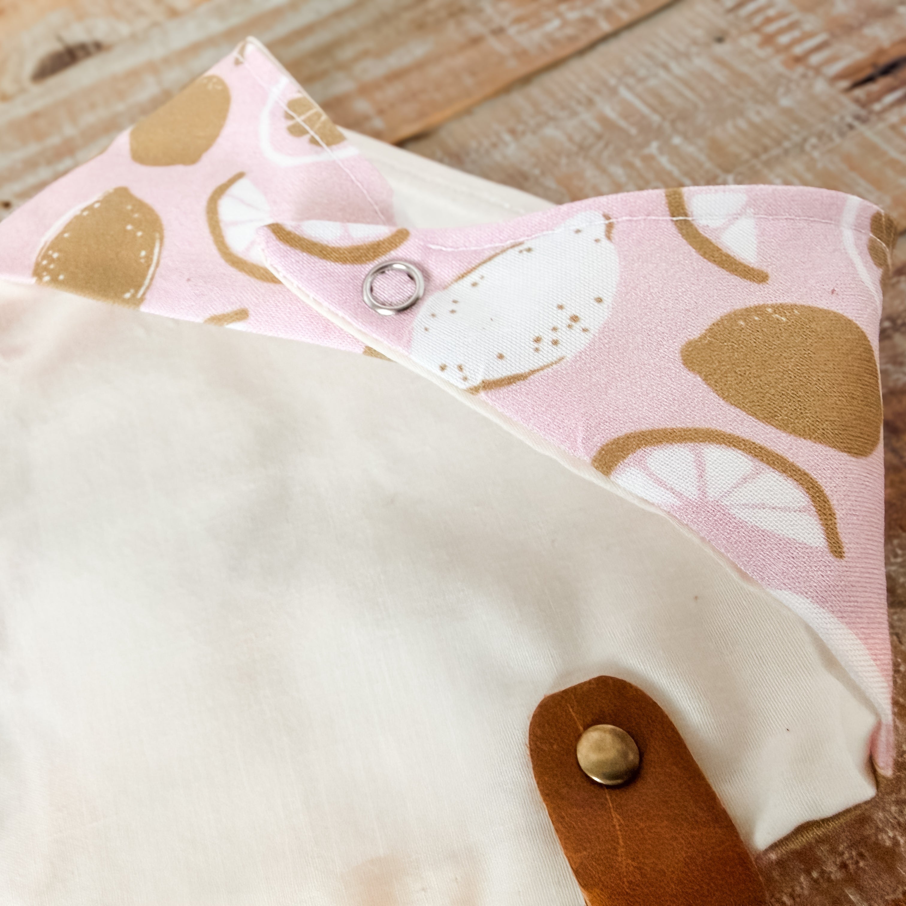 Fabric pouch with pink lemon pattern on a wooden surface