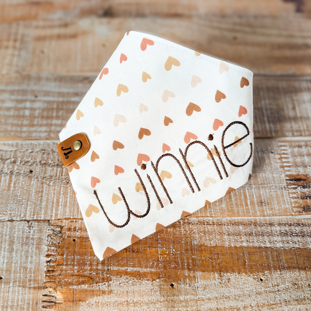 Dog scarf with 'winnie' print on a wooden surface