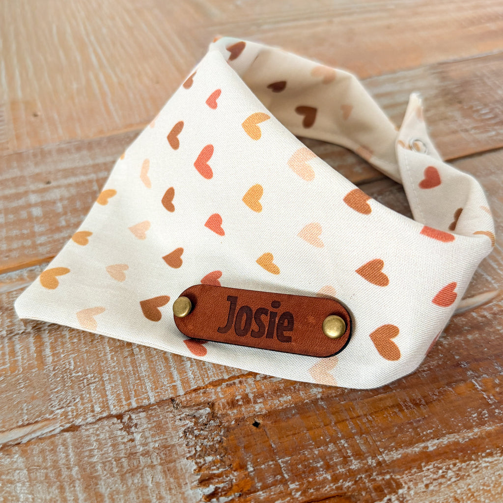 Dog bandana with heart pattern and 'Josie' label on a wooden surface