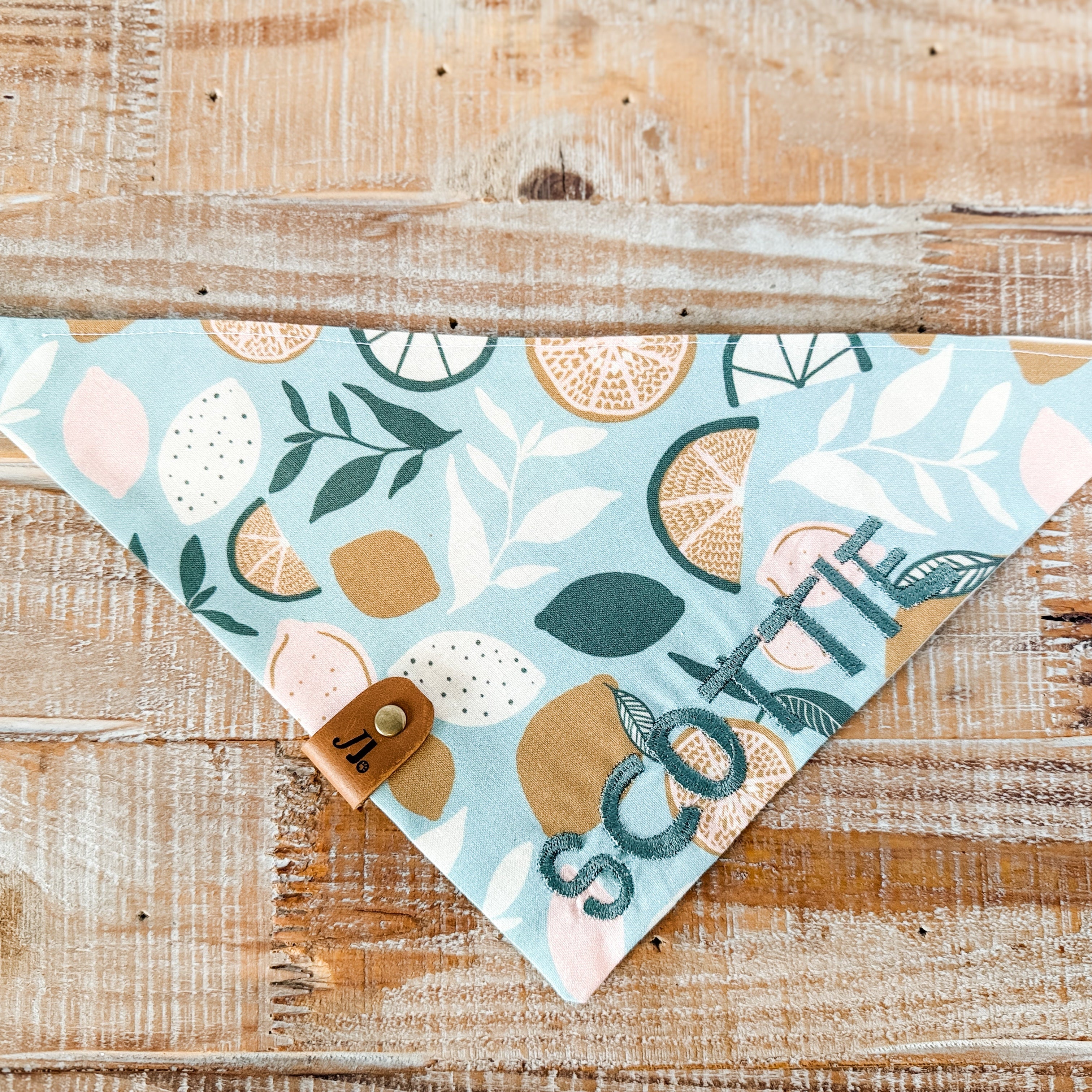 Decorative bandana with floral patterns and 'Scottie' text on a wooden surface