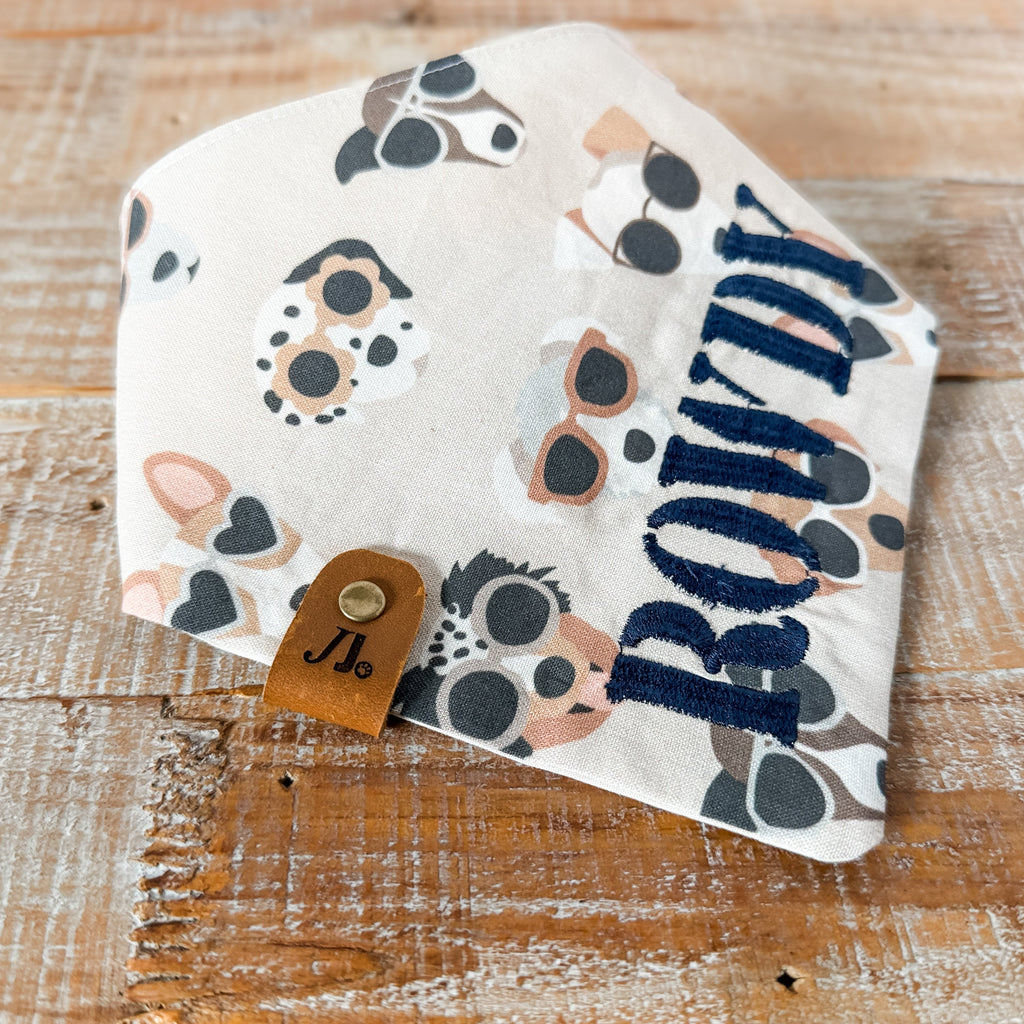 Baby bib with animal prints and 'Rowdy' text on a wooden surface