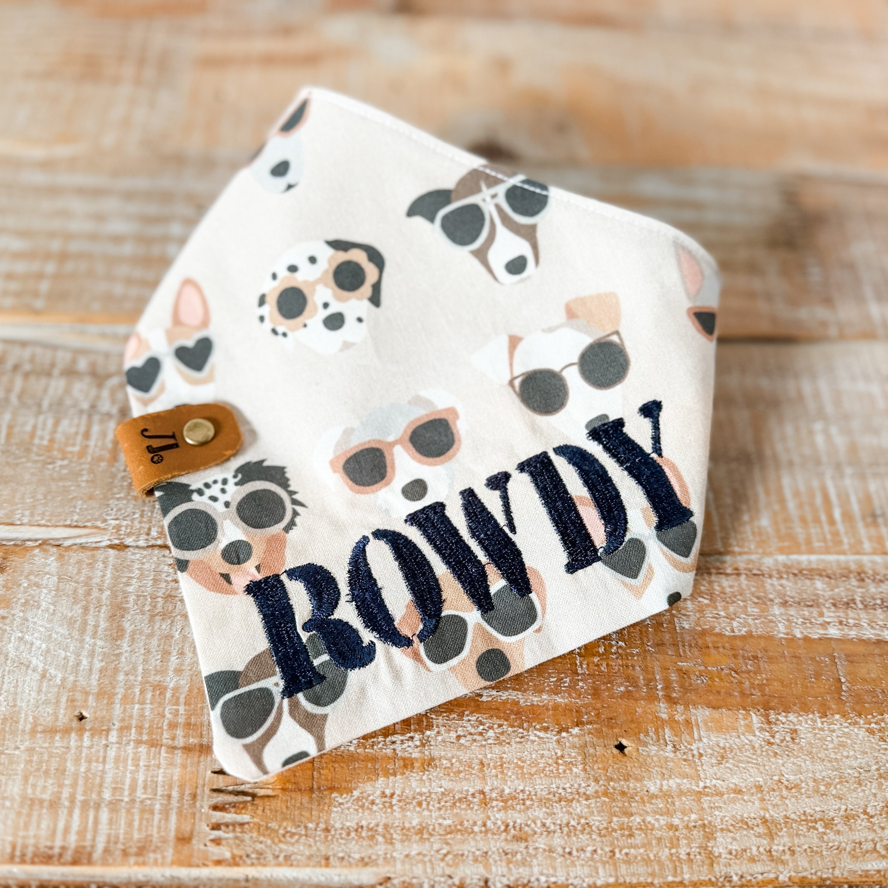 Baby bib with animal print and 'ROWDY' text on a wooden surface