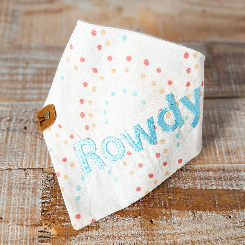 Polka dot bandana with 'Rowdy' printed on it, placed on a wooden surface.