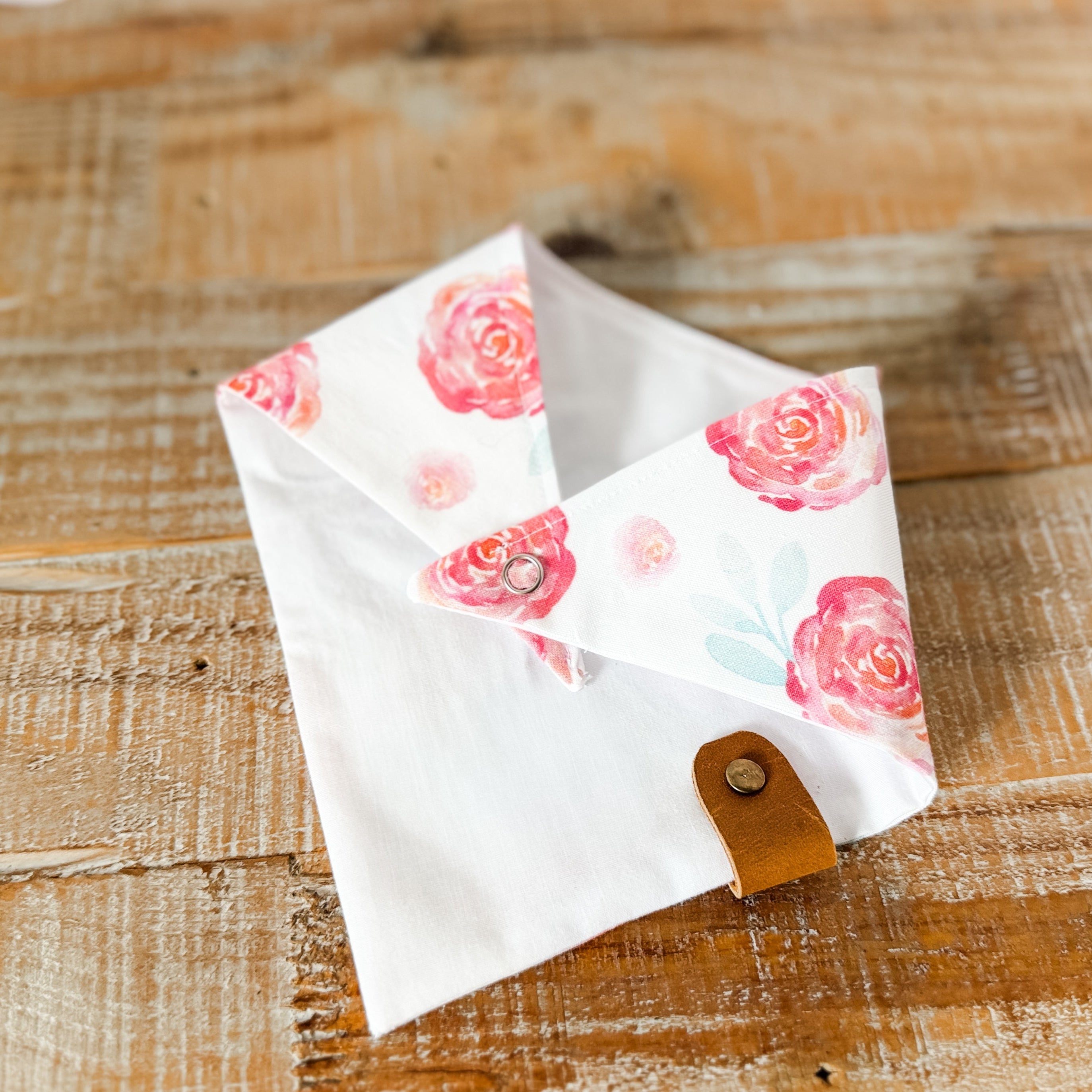 Floral patterned pouch with a leather strap on a wooden surface
