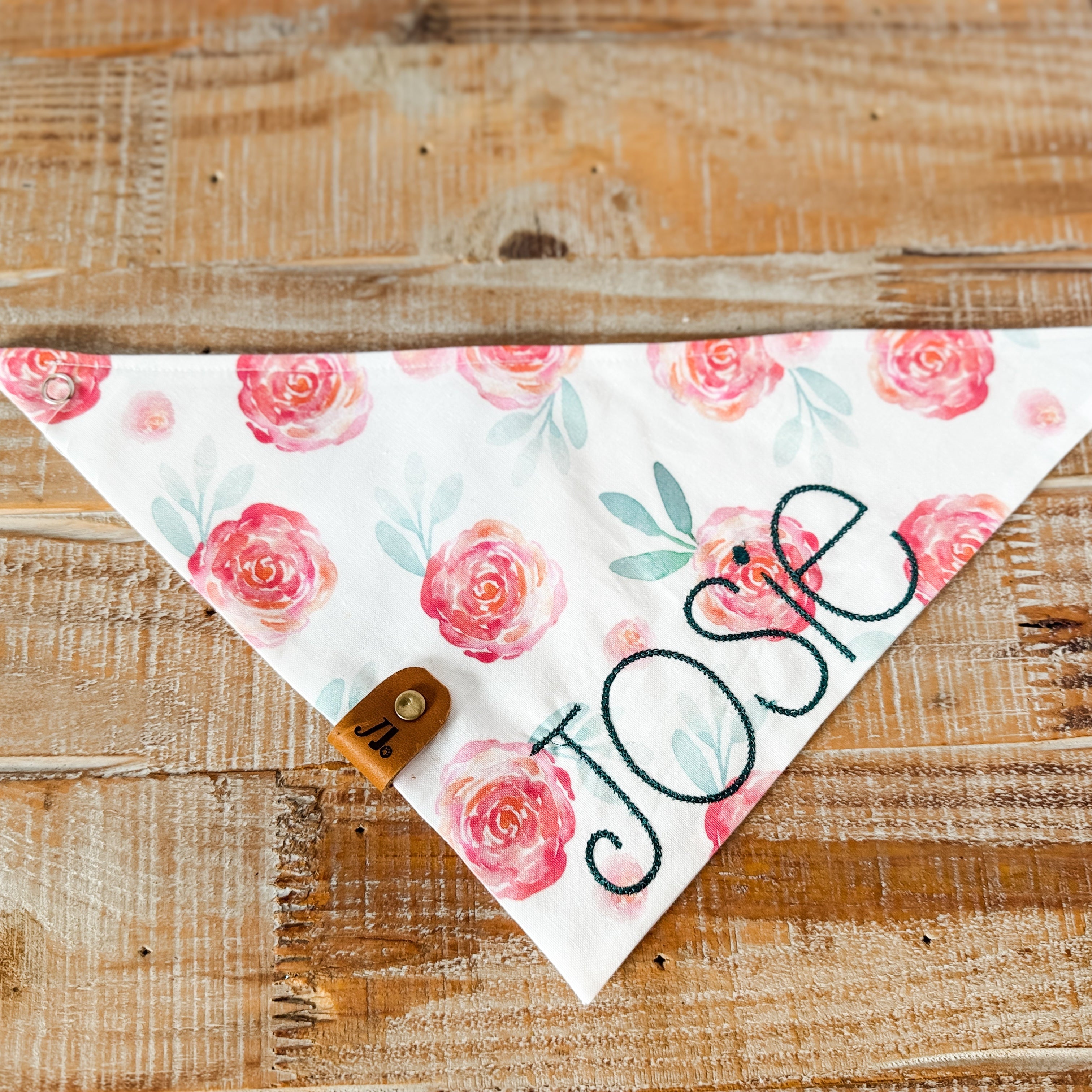 Floral patterned bandana with 'Jose' printed on it, placed on a wooden surface.
