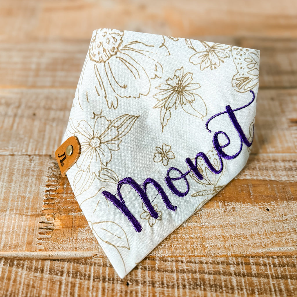 Floral patterned bandana with 'Mone' text on a wooden surface