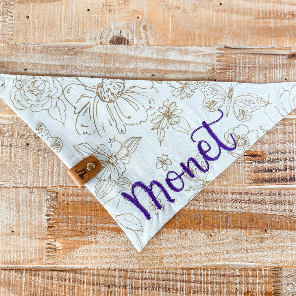 Floral patterned bandana with 'Monet' text on a wooden surface