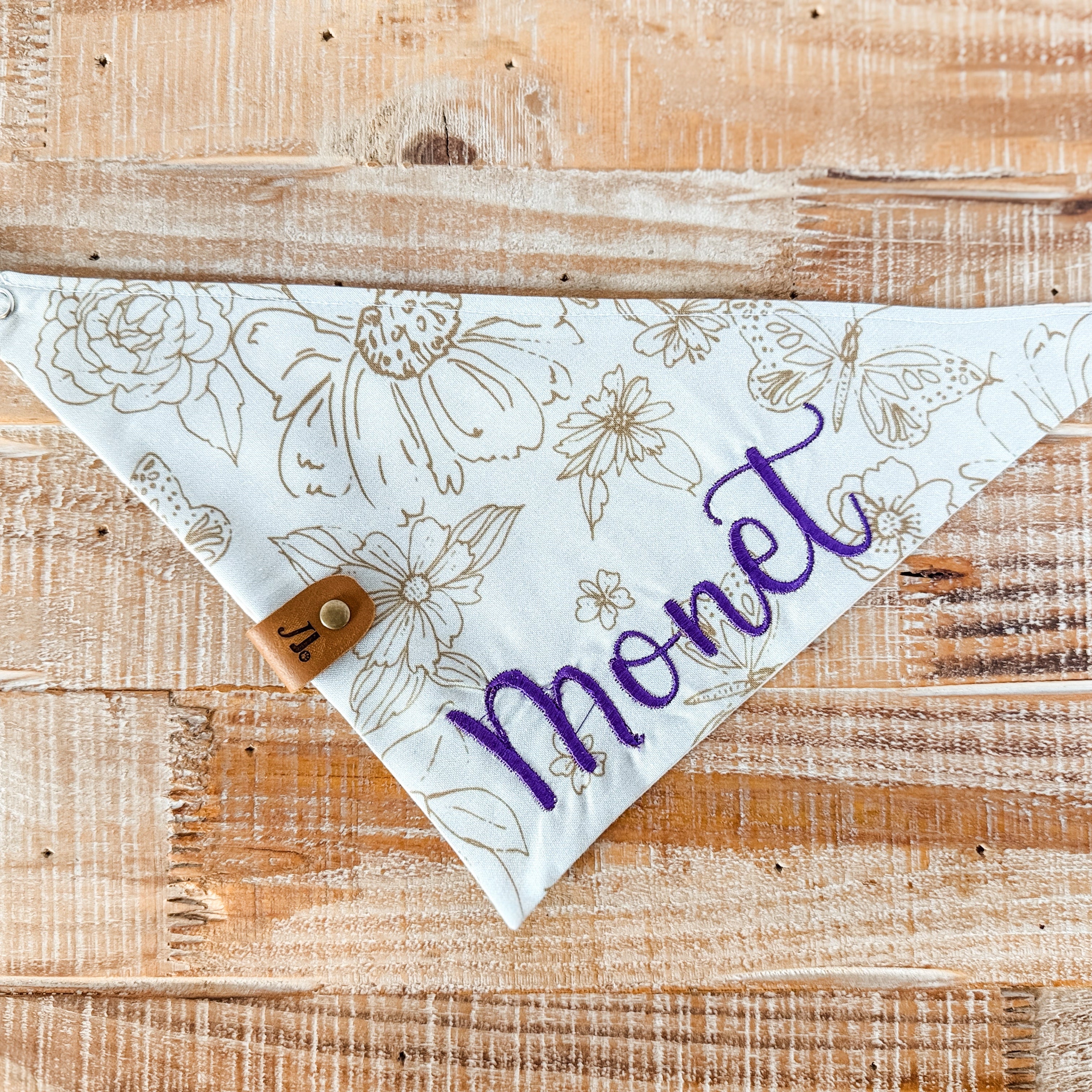 Floral patterned bandana with 'Monet' text on a wooden surface