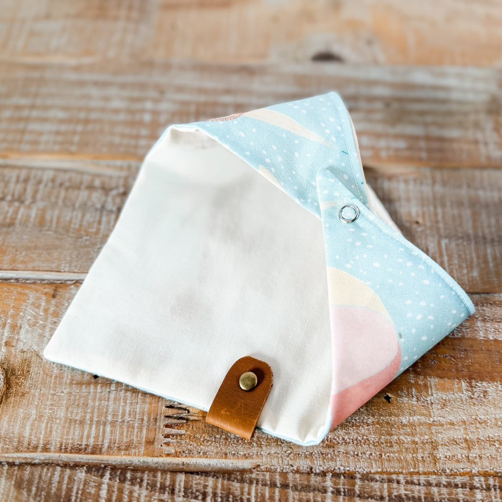 Fabric pouches with a leather strap on a wooden surface