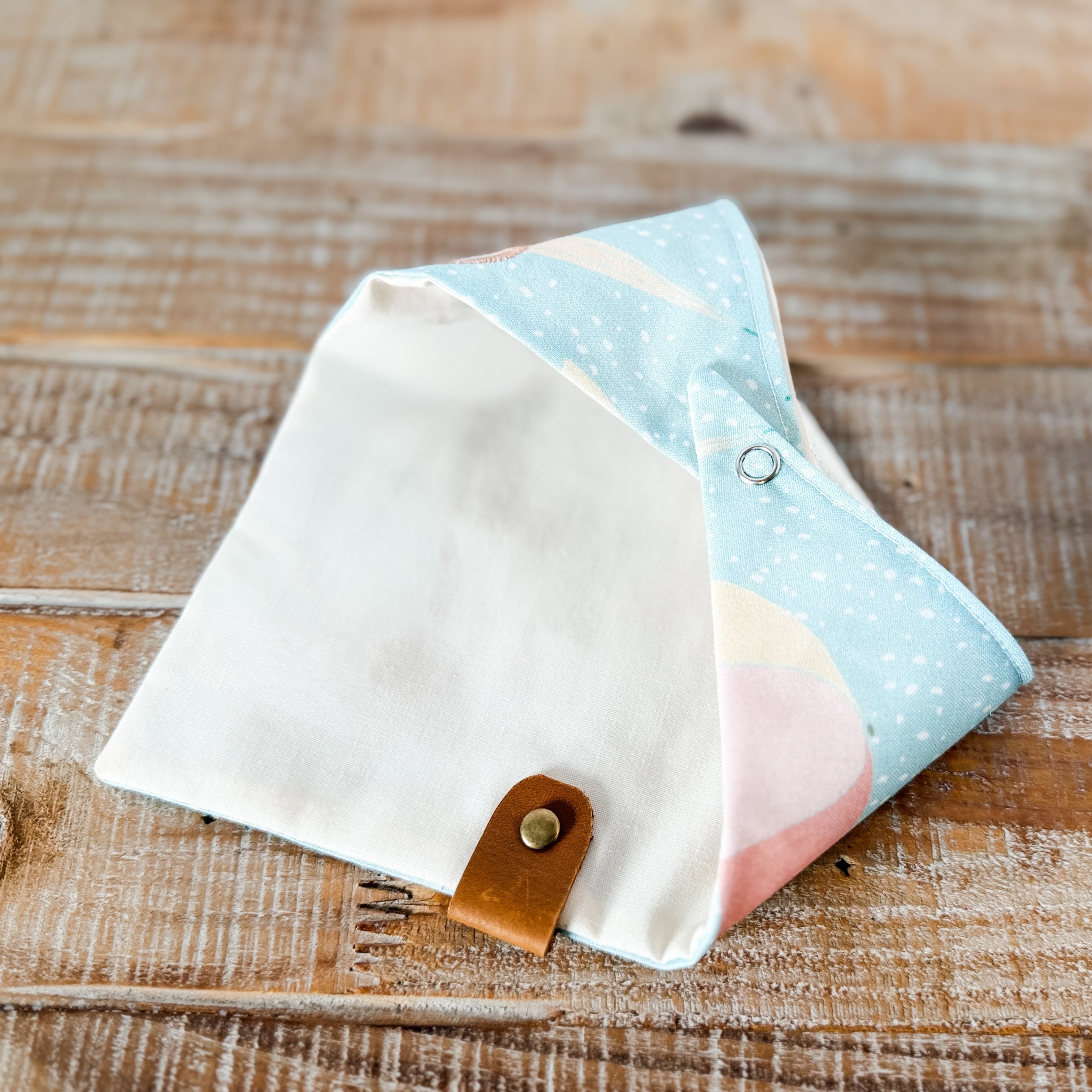 Fabric pouches with a leather strap on a wooden surface