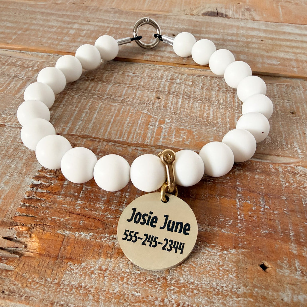 White beaded bracelet with a gold tag on a wooden surface