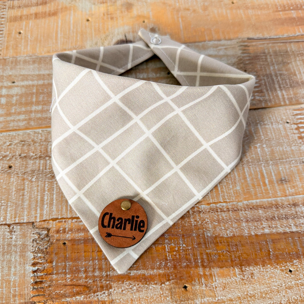 Plaid bandana with a wooden tag labeled 'Charlie' on a wooden surface