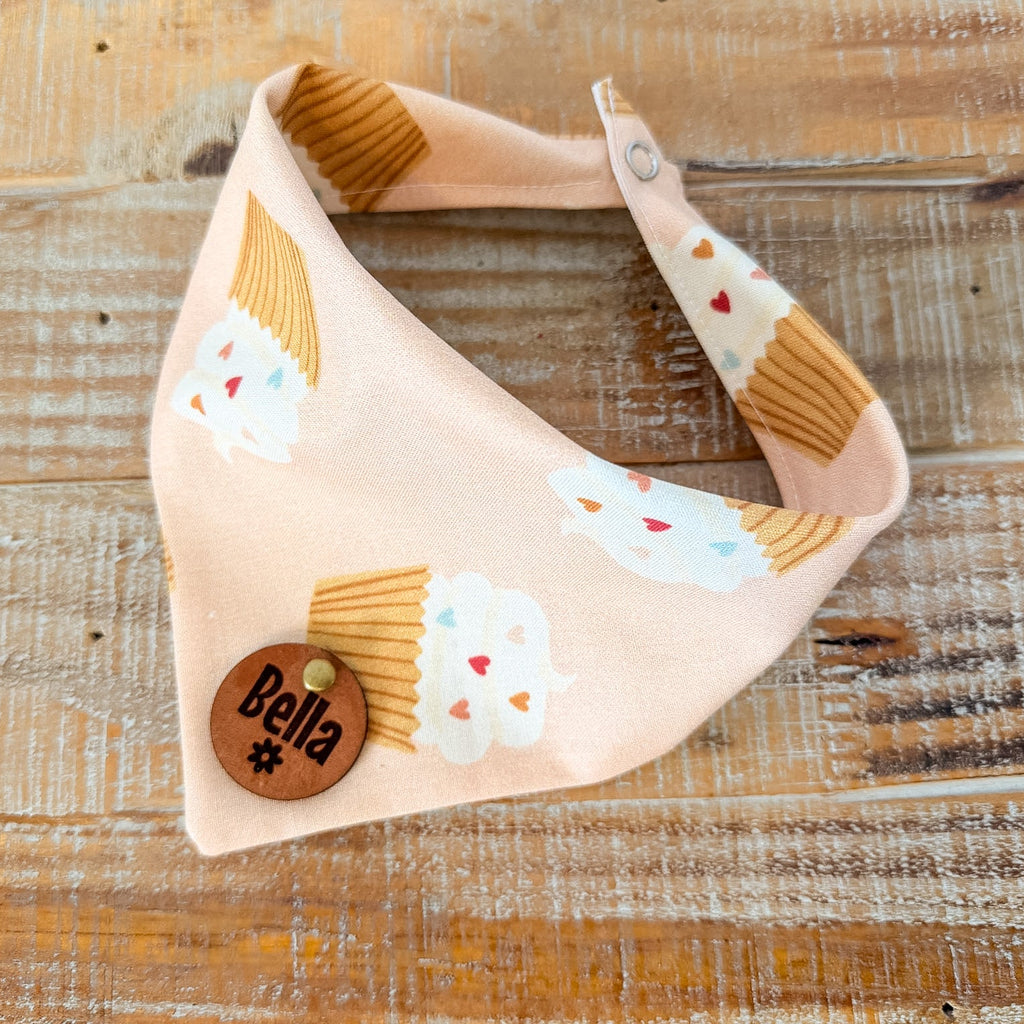 Dog bandana with ice cream cone pattern and 'Bella' tag on a wooden surface